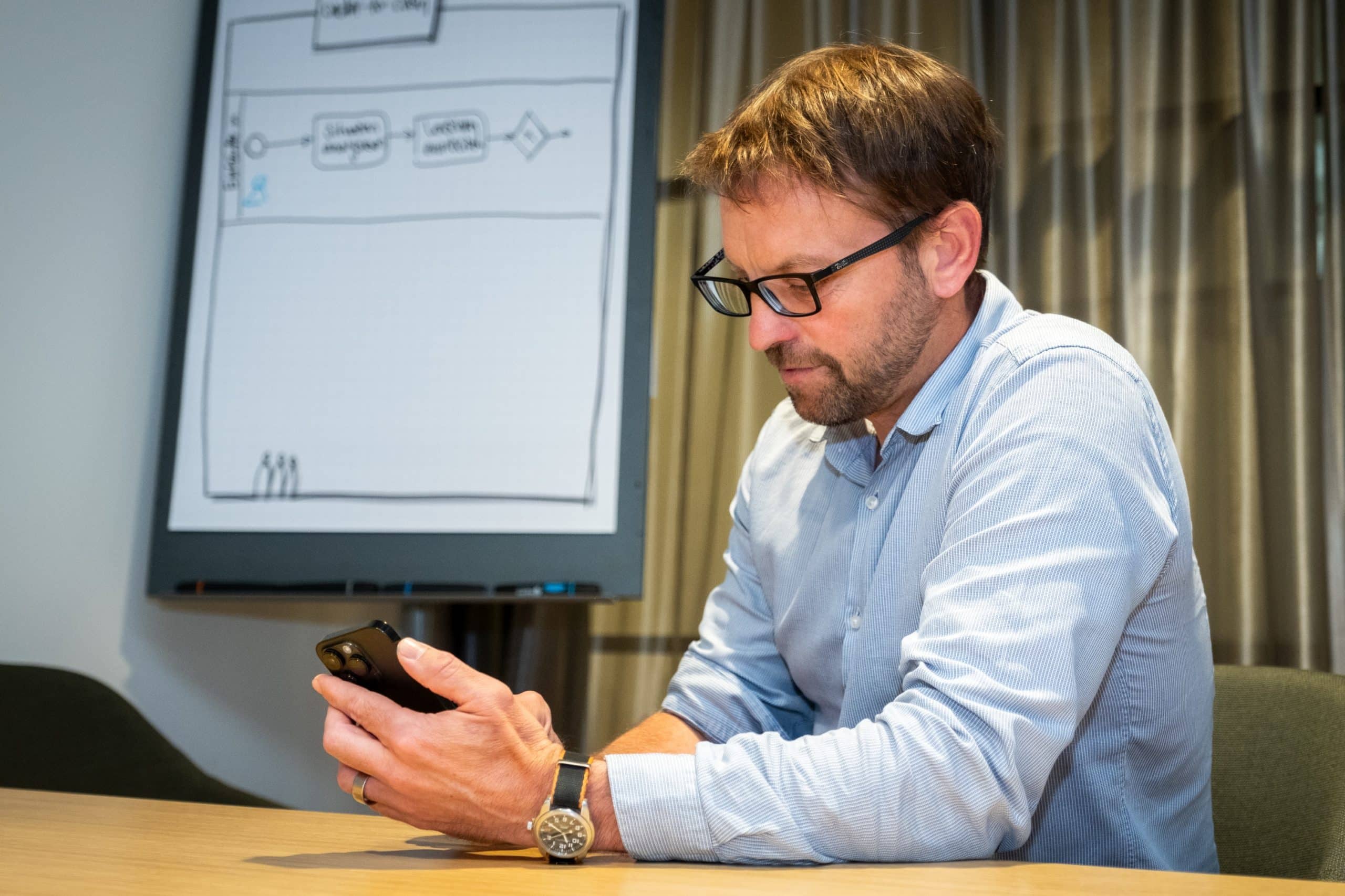 Man with a smartphone in a meeting room at ERNI Switzerland offices.