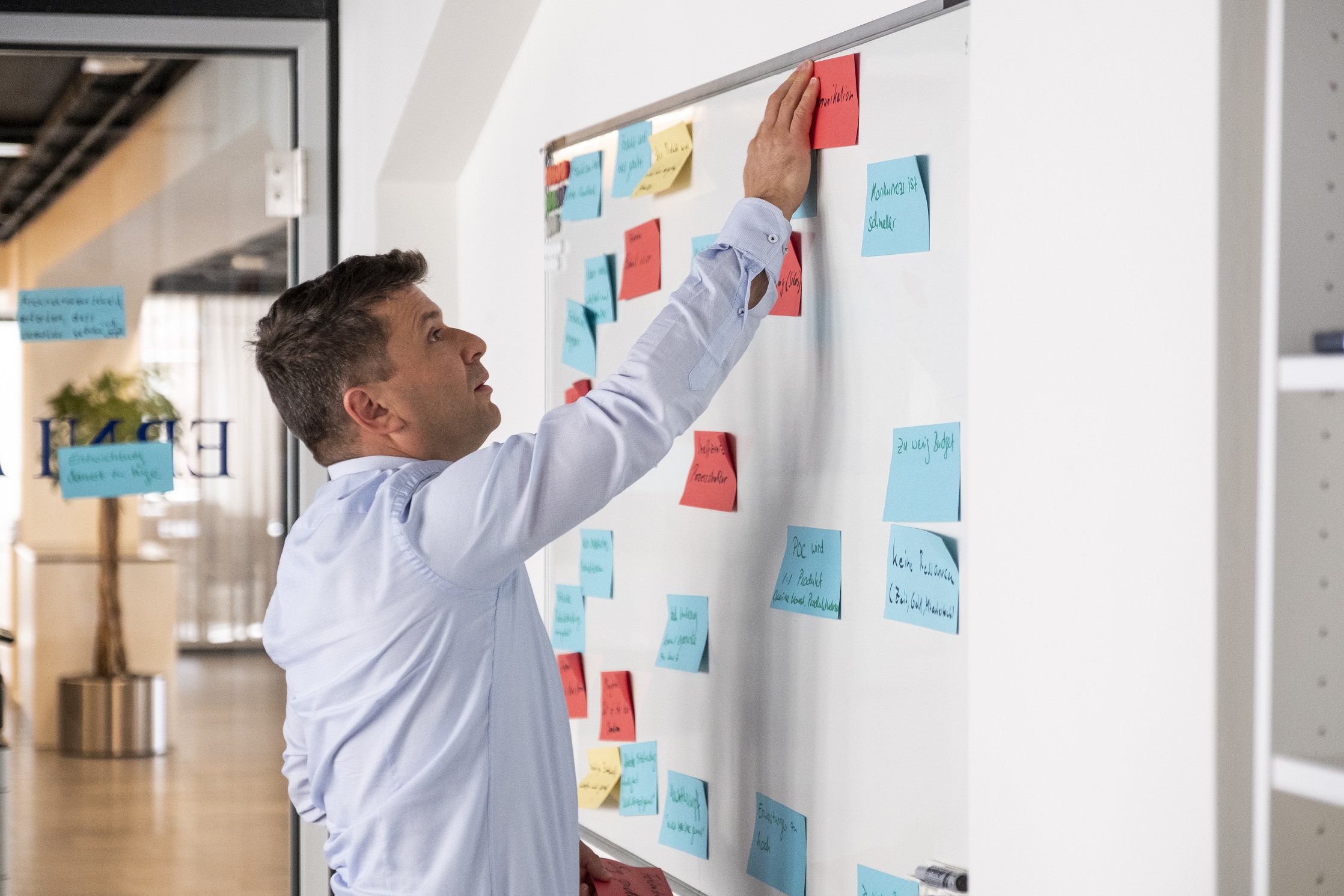 Agile Coach leading a collaborative team discussion, illustrating how organisations can adapt to uncertainty through continuous learning, feedback, and outcome-focused leadership.