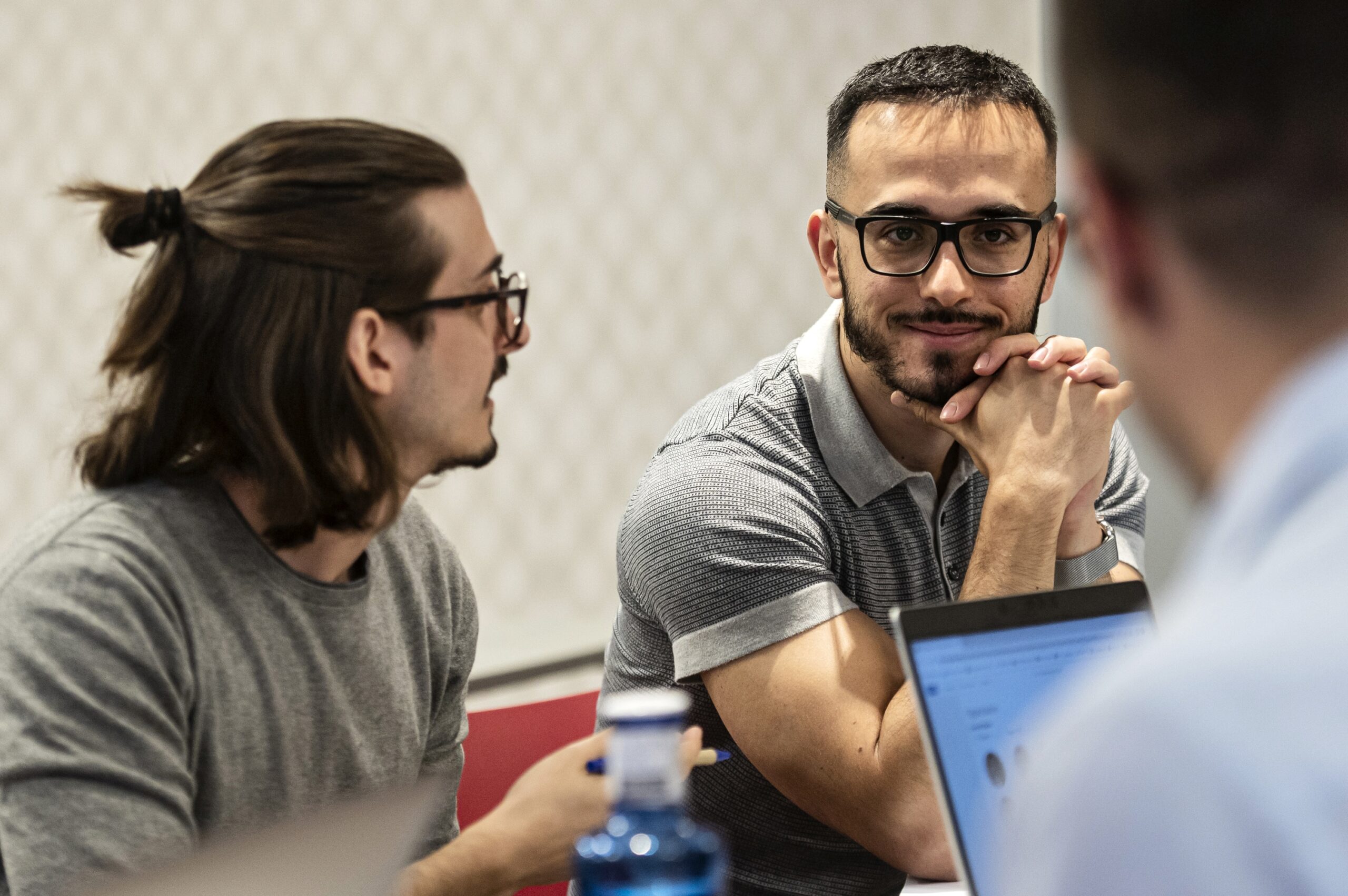 Software engineers collaborating in a modern office, reviewing application migration plans and test automation strategies on laptops and a shared screen.