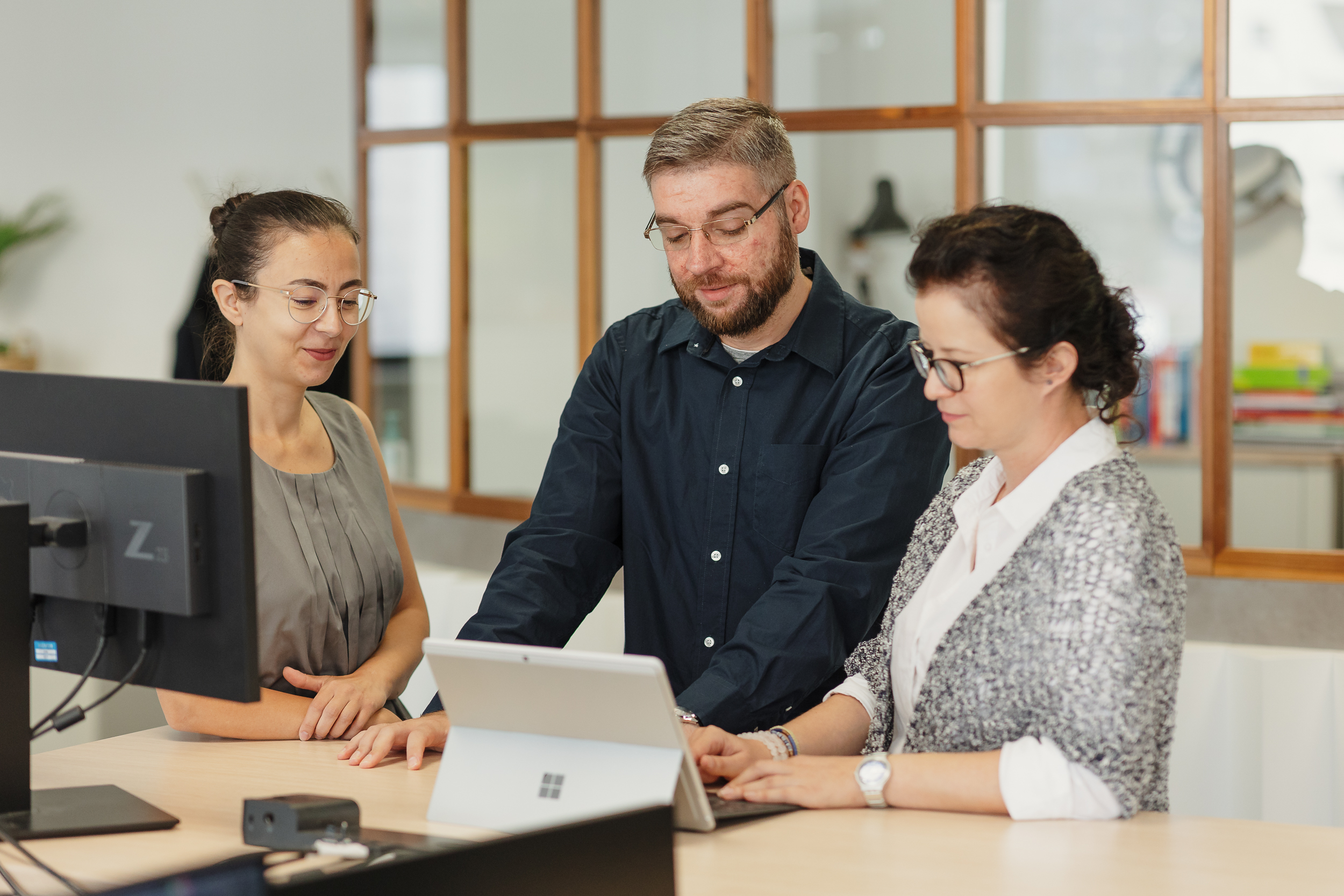 Employees collaborating in front of a tablet while discussing AI platform governance and enterprise technology